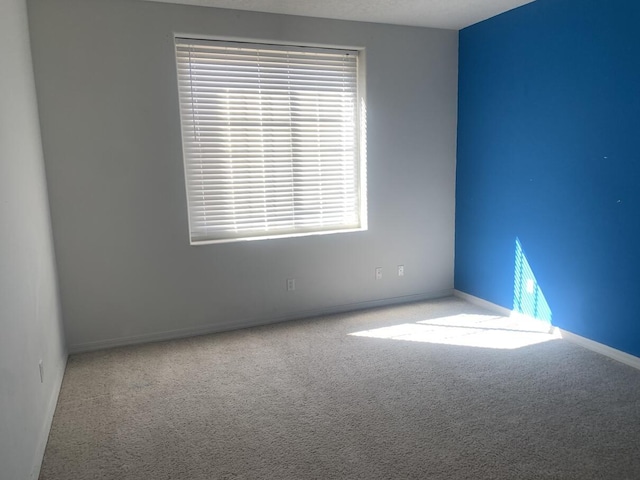 carpeted empty room featuring baseboards
