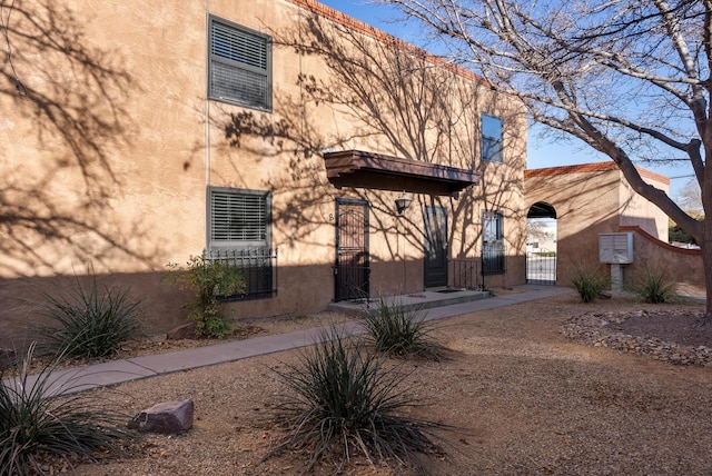 exterior space featuring a gate, fence, and stucco siding