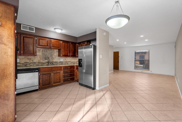 kitchen featuring light tile patterned floors, visible vents, a sink, stainless steel appliances, and backsplash