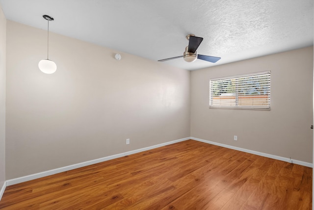 spare room with baseboards, light wood-style floors, and ceiling fan