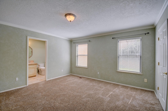 unfurnished bedroom with carpet, baseboards, ensuite bath, ornamental molding, and a textured ceiling