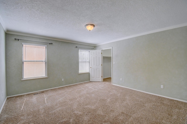 carpeted spare room with crown molding, baseboards, and a textured ceiling