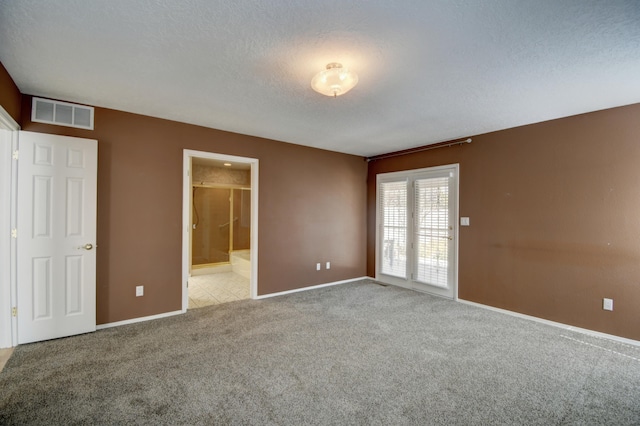 interior space with baseboards, visible vents, ensuite bathroom, a textured ceiling, and carpet flooring