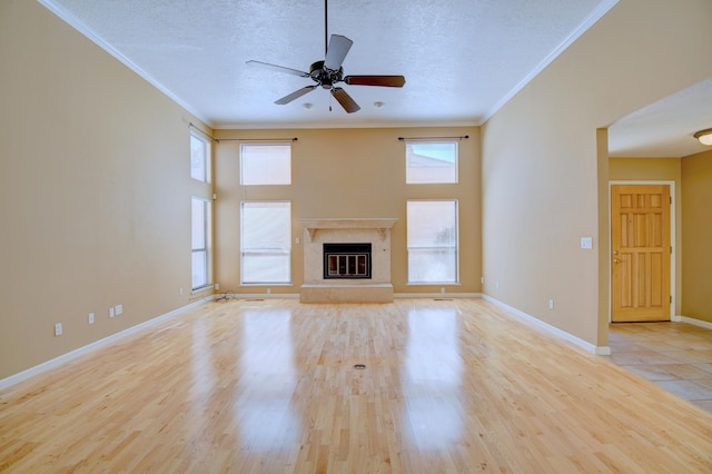 unfurnished living room featuring baseboards, wood finished floors, a textured ceiling, and ornamental molding