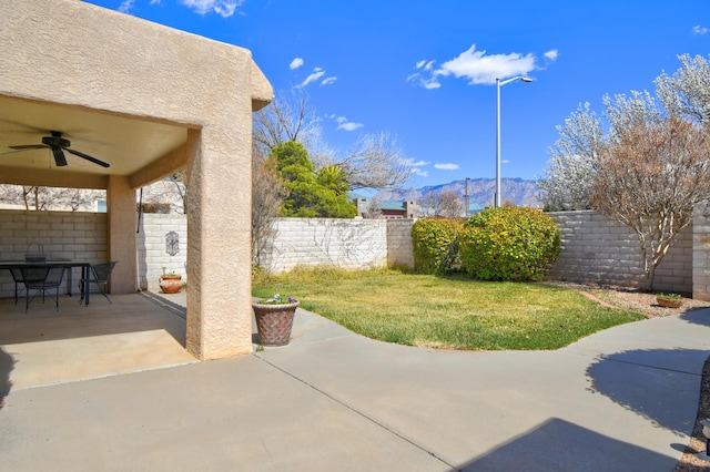 view of patio / terrace featuring a mountain view, a fenced backyard, outdoor dining space, and a ceiling fan