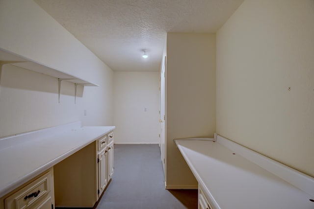 interior space featuring baseboards, open shelves, light countertops, a textured ceiling, and cream cabinets