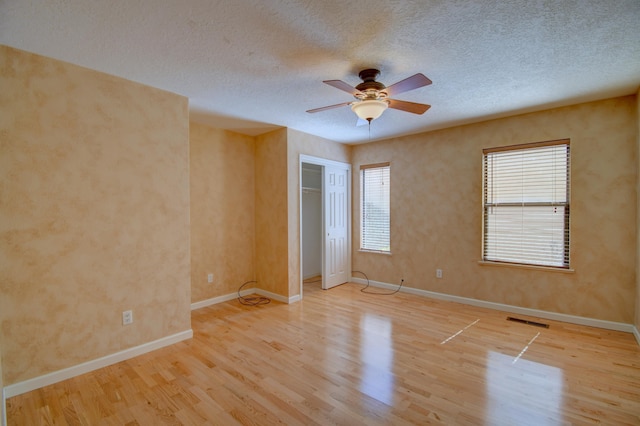 spare room featuring a textured ceiling, wood finished floors, visible vents, and ceiling fan