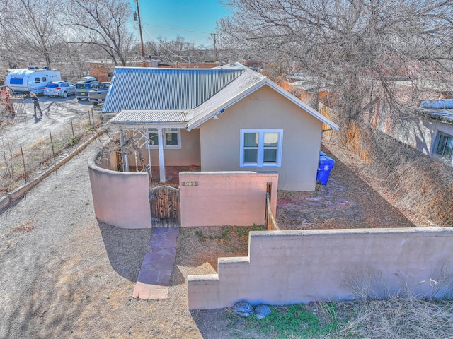 506 Onate Pl, Santa Fe, NM 87501 - exterior space featuring metal roof, a fenced front yard, stucco siding, and a gate