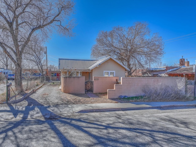 506 Onate Pl, Santa Fe, NM 87501 - view of side of home with a fenced front yard, metal roof, and stucco siding
