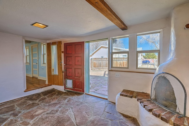 506 Onate Pl, Santa Fe, NM 87501 - doorway with beamed ceiling, a textured ceiling, and stone flooring