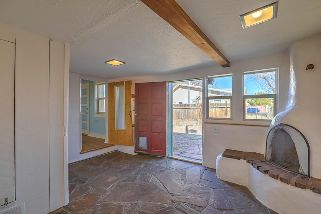 506 Onate Pl, Santa Fe, NM 87501 - entrance foyer featuring visible vents, beam ceiling, stone floors, and a textured ceiling