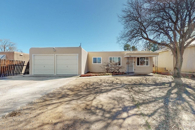 view of front of home with fence, a garage, driveway, and stucco siding