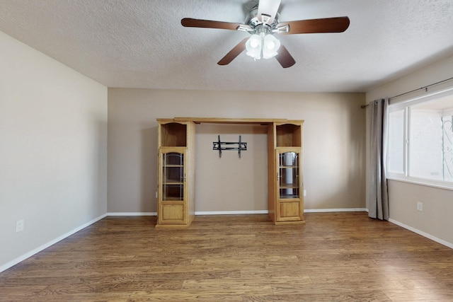 interior space featuring baseboards, a textured ceiling, ceiling fan, and light wood finished floors