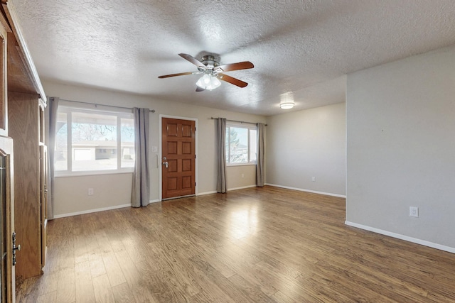 interior space featuring a textured ceiling, baseboards, ceiling fan, and wood finished floors