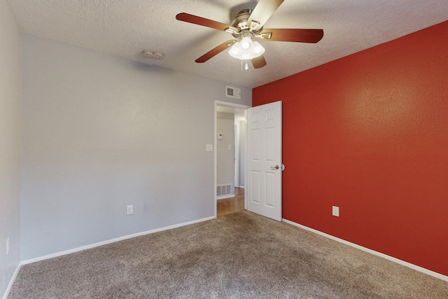 unfurnished room featuring visible vents, a textured ceiling, carpet, baseboards, and ceiling fan