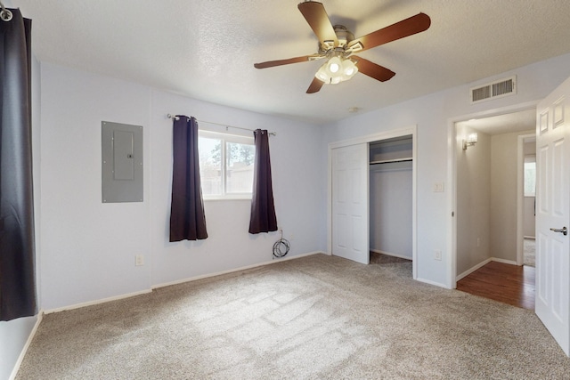 unfurnished bedroom with visible vents, carpet, electric panel, a closet, and a textured ceiling