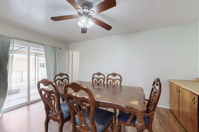 dining area with a textured ceiling, light wood-style flooring, and a ceiling fan