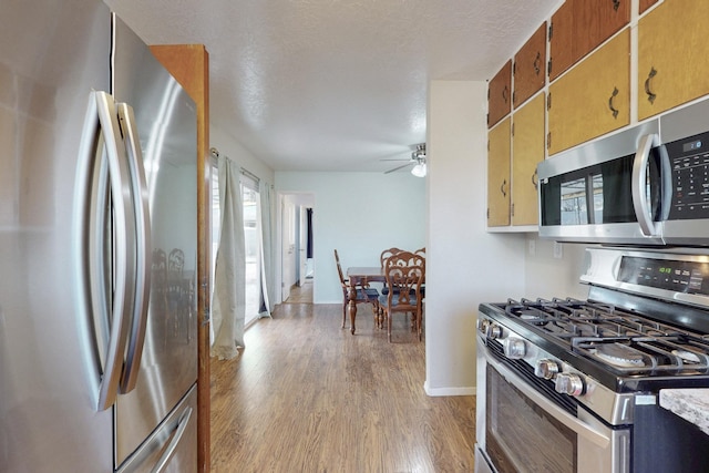 kitchen with light wood-style flooring, a textured ceiling, stainless steel appliances, light countertops, and ceiling fan