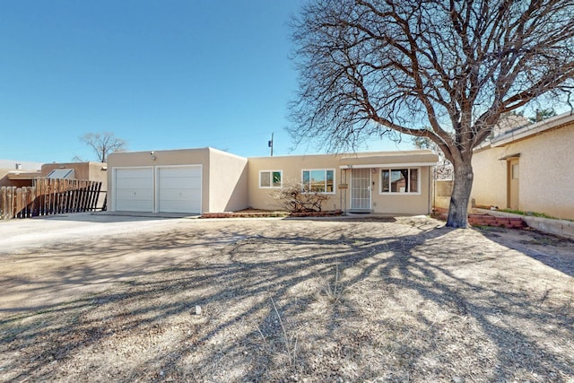 view of front of house with fence, a garage, driveway, and stucco siding