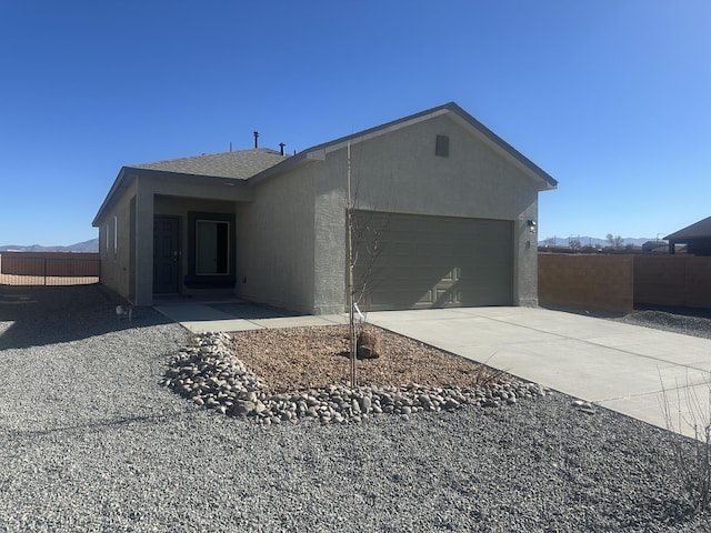 single story home featuring concrete driveway, fence, a garage, and stucco siding