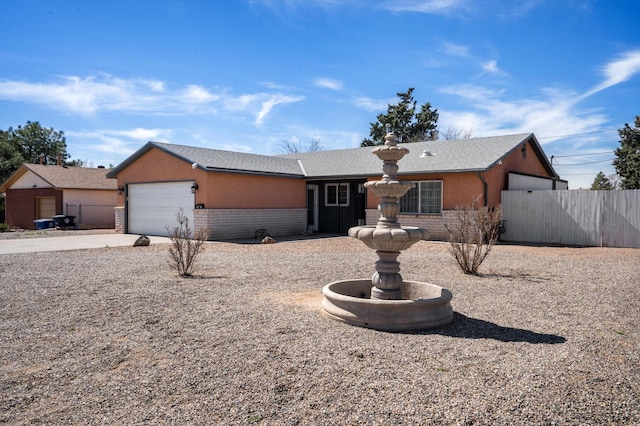 ranch-style home with stucco siding, brick siding, an attached garage, and fence