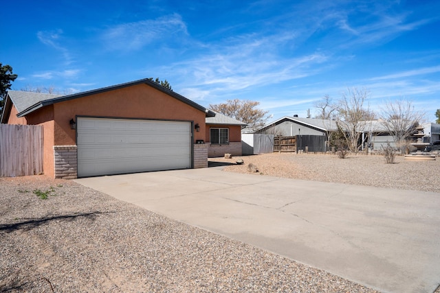 view of front of house with stucco siding, driveway, an attached garage, and fence