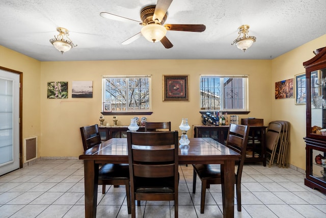 dining area with light tile patterned floors, baseboards, a textured ceiling, and a ceiling fan