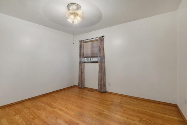 unfurnished room with light wood-style flooring, a ceiling fan, and baseboards