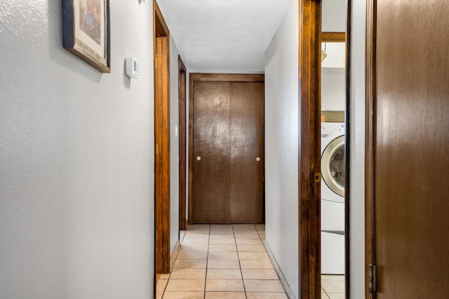 hall featuring washer / dryer, light tile patterned flooring, and a textured ceiling