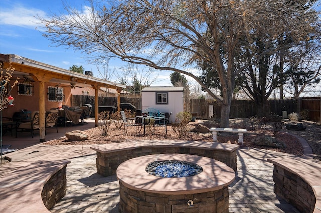 view of patio / terrace with a fenced backyard, an outdoor fire pit, a storage shed, an outdoor structure, and ceiling fan