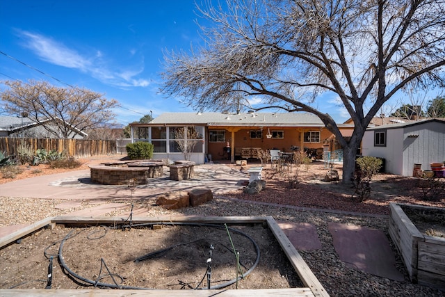 back of property featuring a fire pit, a sunroom, a patio, and fence