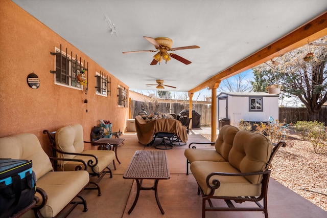 view of patio with an outdoor living space, an outdoor structure, a fenced backyard, and a ceiling fan