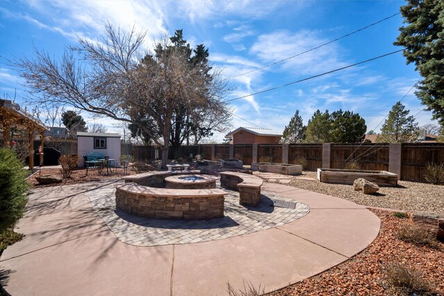 view of patio with an outbuilding, a shed, a fire pit, and a fenced backyard