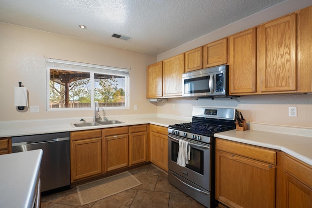 101 Colinas Ave NE, Albuquerque, NM 87113 - kitchen with visible vents, a sink, light countertops, appliances with stainless steel finishes, and a textured ceiling