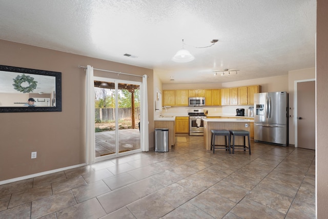 101 Colinas Ave NE, Albuquerque, NM 87113 - kitchen featuring visible vents, a kitchen island, light countertops, stainless steel appliances, and a sink