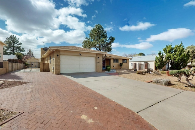 ranch-style home featuring a gate, fence, concrete driveway, a garage, and brick siding