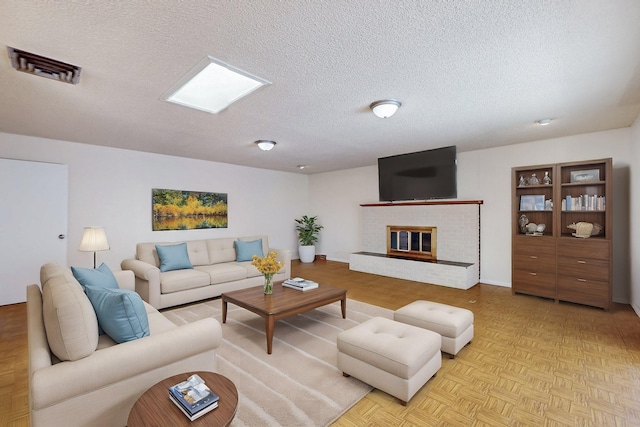 living room with visible vents, a textured ceiling, and a brick fireplace