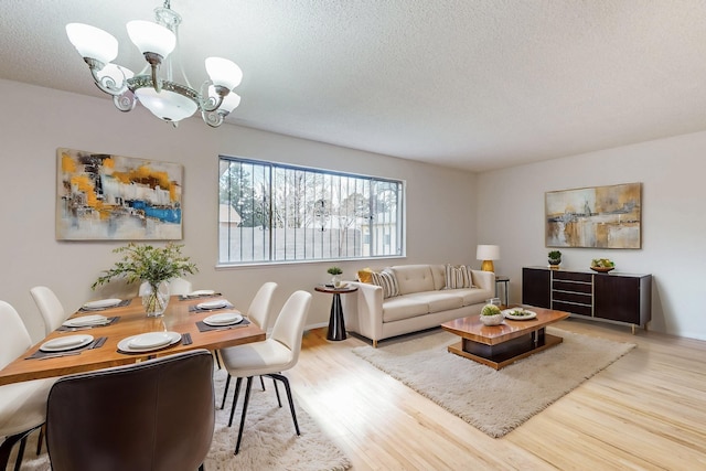 dining space with a chandelier, a textured ceiling, and wood finished floors