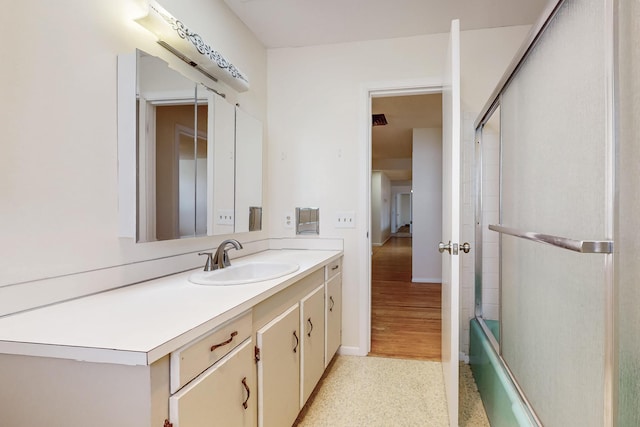 bathroom featuring vanity, baseboards, and bath / shower combo with glass door