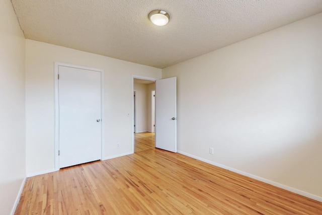 unfurnished bedroom with a textured ceiling, baseboards, and light wood-style floors