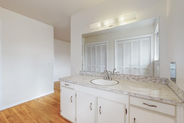 bathroom with vanity, wood finished floors, and baseboards