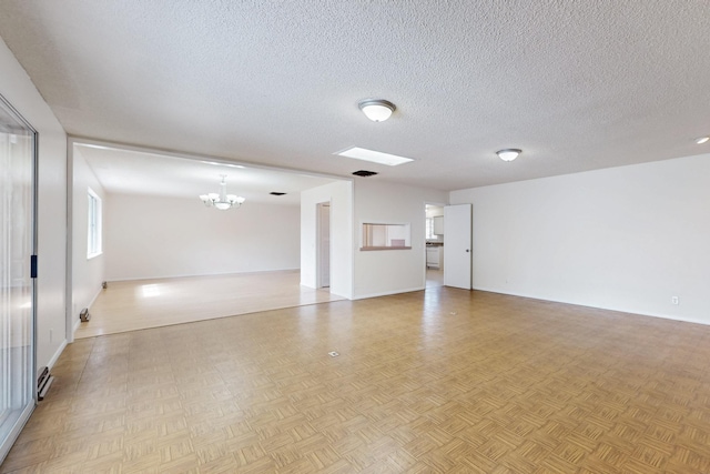 spare room featuring visible vents, a notable chandelier, and a textured ceiling