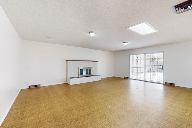 unfurnished living room with visible vents, a textured ceiling, and baseboards