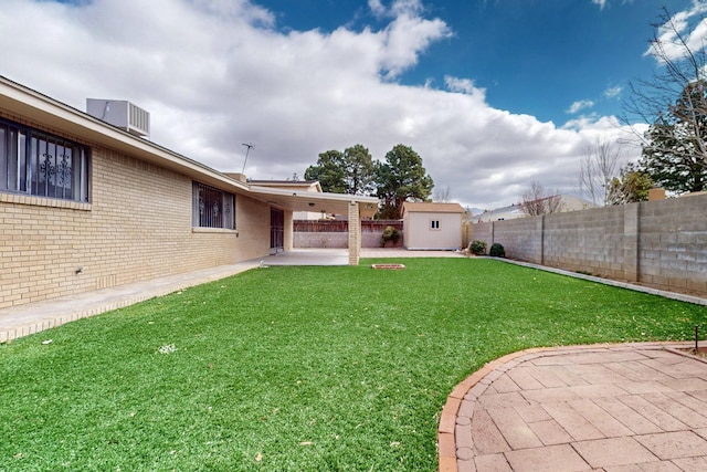 view of yard with an outbuilding, central AC, a fenced backyard, a shed, and a patio area