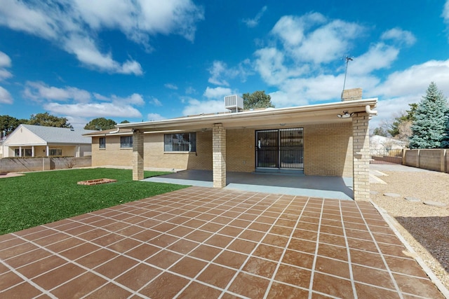 back of property with a lawn, a patio, central AC, fence, and brick siding