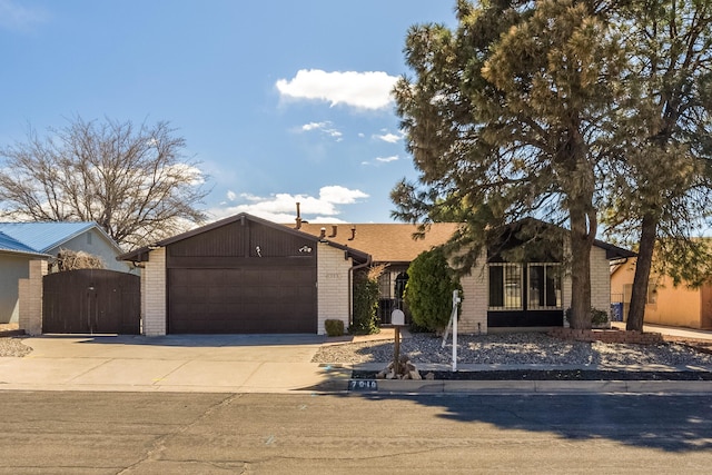 view of front facade featuring concrete driveway, a gate, brick siding, and a garage