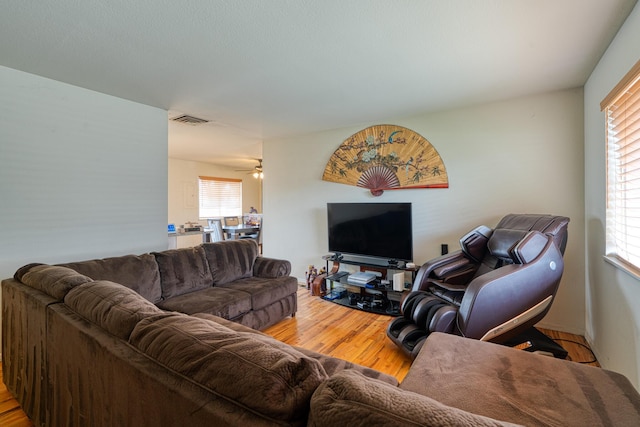 living area featuring visible vents, plenty of natural light, a ceiling fan, and wood finished floors