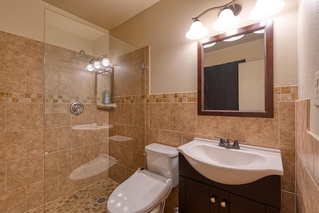 bathroom featuring vanity, tile walls, toilet, and a tile shower