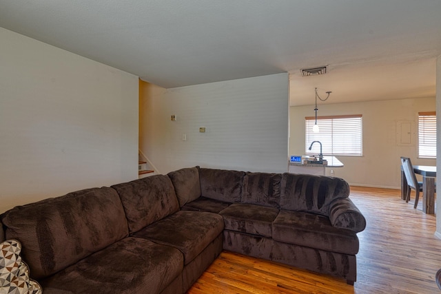 living area featuring stairway, visible vents, and light wood finished floors