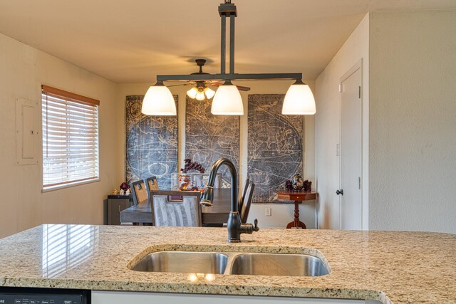 kitchen with pendant lighting, a ceiling fan, a sink, dishwashing machine, and light stone countertops